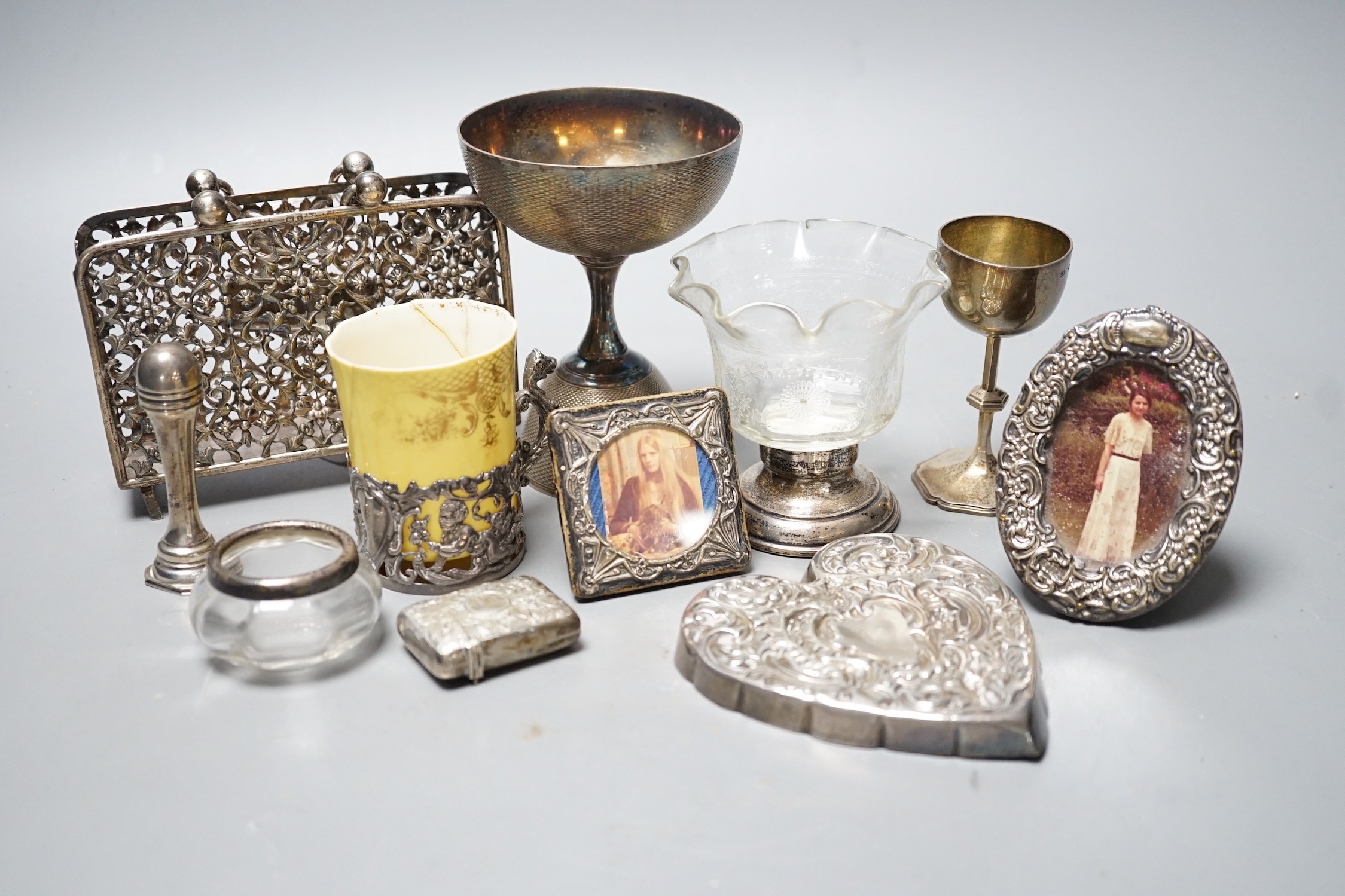 A small group of collectable items including a silver stationary rack, Laurence Emanuel, Birmingham, 1901, height 9.7cm, a silver communion goblet, silver mounted porcelain coffee cup, silver mounted glass vase, silver v